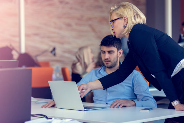 Skilled professional blonde female CEO explaining to young male employee requires and strategy