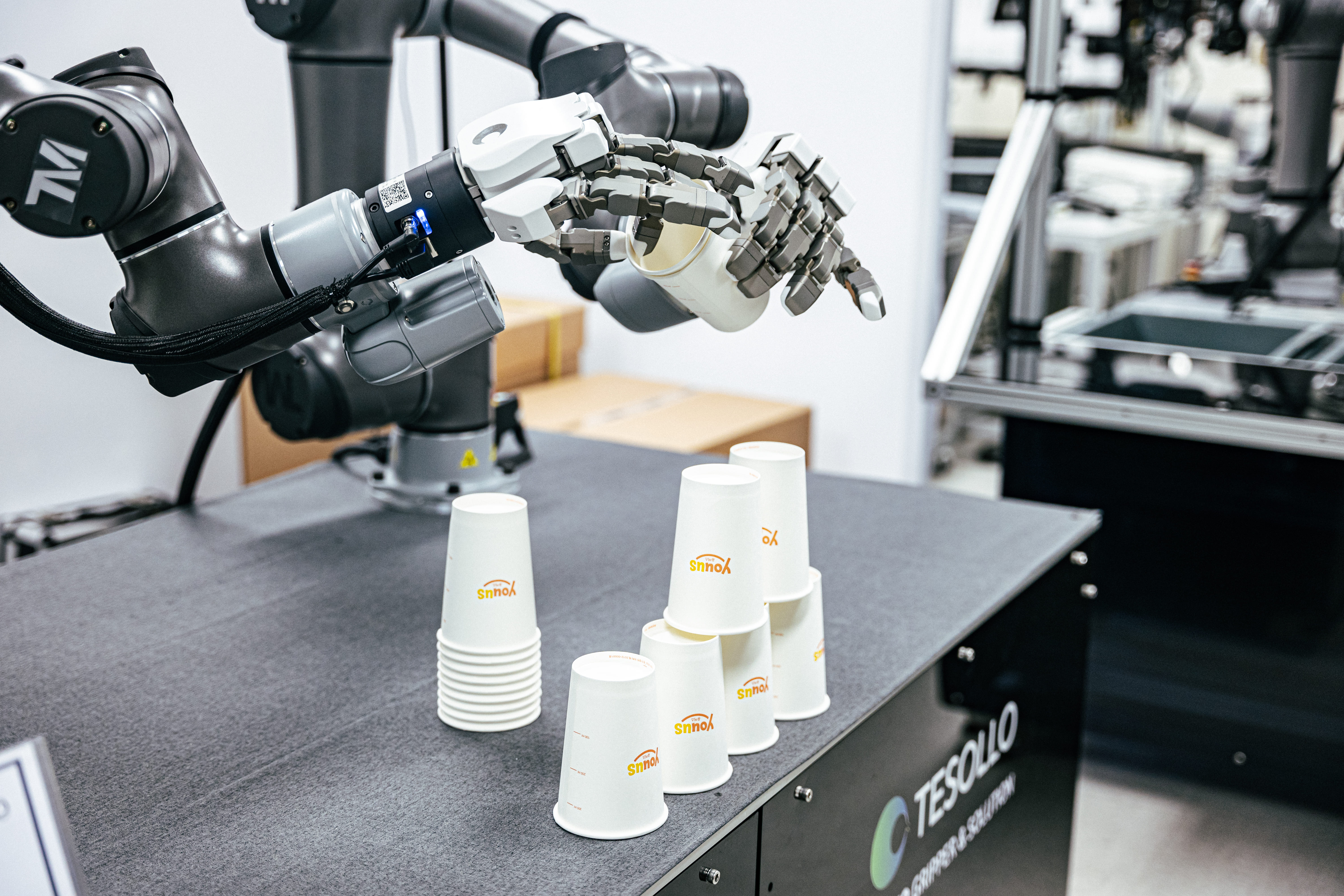 테솔로의 5지 로봇 핸드가 양손으로 종이컵 탑을 쌓고 있다.