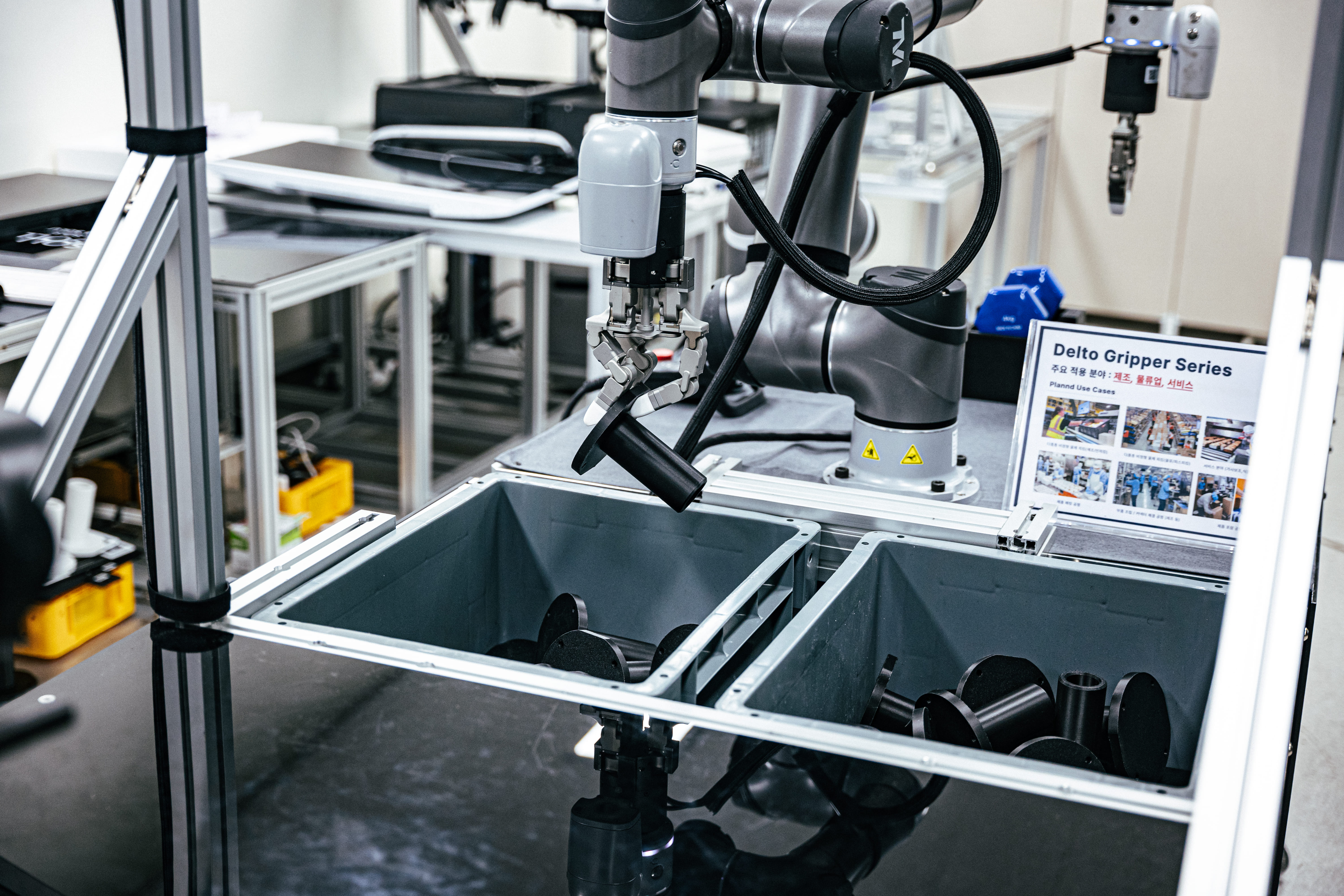 테솔로의 3지 그리퍼가 손가락을 섬세하게 구부린 채 물건을 옮기고 있다.